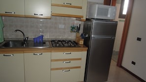 A kitchen with a sink, stove, microwave, and refrigerator. - Spacious Flat Perfect for Enjoying Your Vacations (San Michele al Tagliamento)