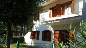 A two-story building with wooden shutters, a white exterior, and a visible balcony. - Villa With Private Garden and Barbeque - Beahost (San Michele al Tagliamento)