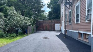 Un camino estrecho que lleva a una casa con un muro de ladrillo y una puerta de garaje.