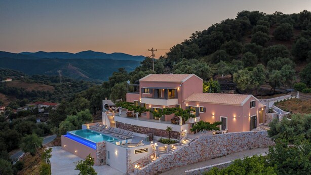 Una villa de estilo mediterráneo con piscina, muros de piedra y jardines en terrazas.