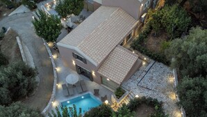 Vista aérea de una casa con piscina, mobiliario de exterior y un camino de piedra.