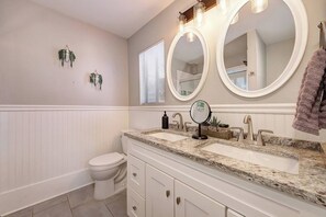 Une salle de bain avec deux lavabos, des toilettes et deux grands miroirs.