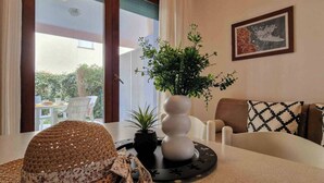 A room with a dining table, a potted plant, a woven hat, and a framed artwork on the wall. - Great Flat Close to the Beach With Parking (San Michele al Tagliamento)