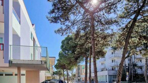 A residential street with modern buildings, a parked car, and trees. - Great Flat Close to the Beach With Parking (San Michele al Tagliamento)