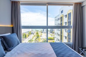 Une chambre d’hôtel avec une grande fenêtre, un lit et une vue sur le paysage urbain.