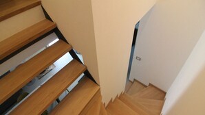 Uma escadaria de madeira com design moderno que leva a um quarto com porta branca.