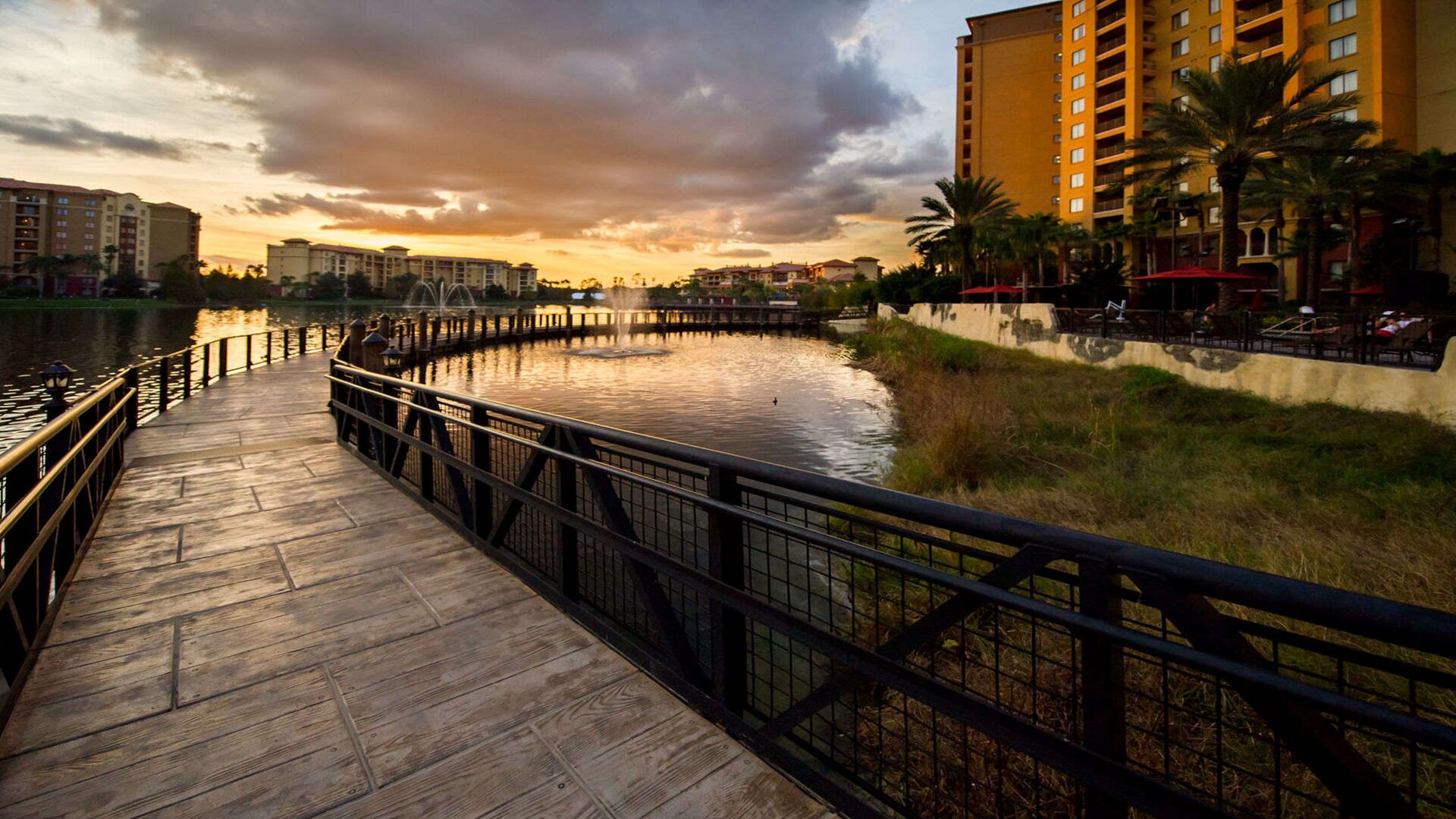 A wooden boardwalk by a body of water with a sunset in the background.