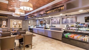 A restaurant with a counter, menu boards, and a refrigerated display of food items.