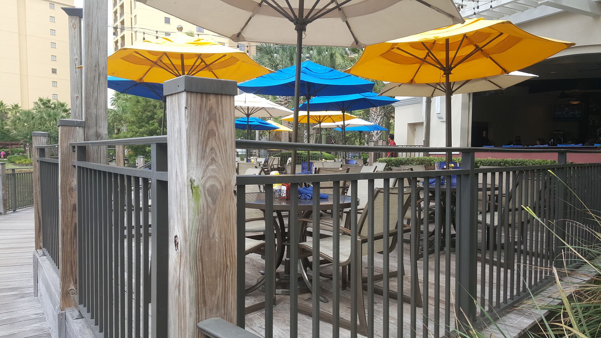 An outdoor seating area with tables and chairs, surrounded by a wooden fence and metal railings.