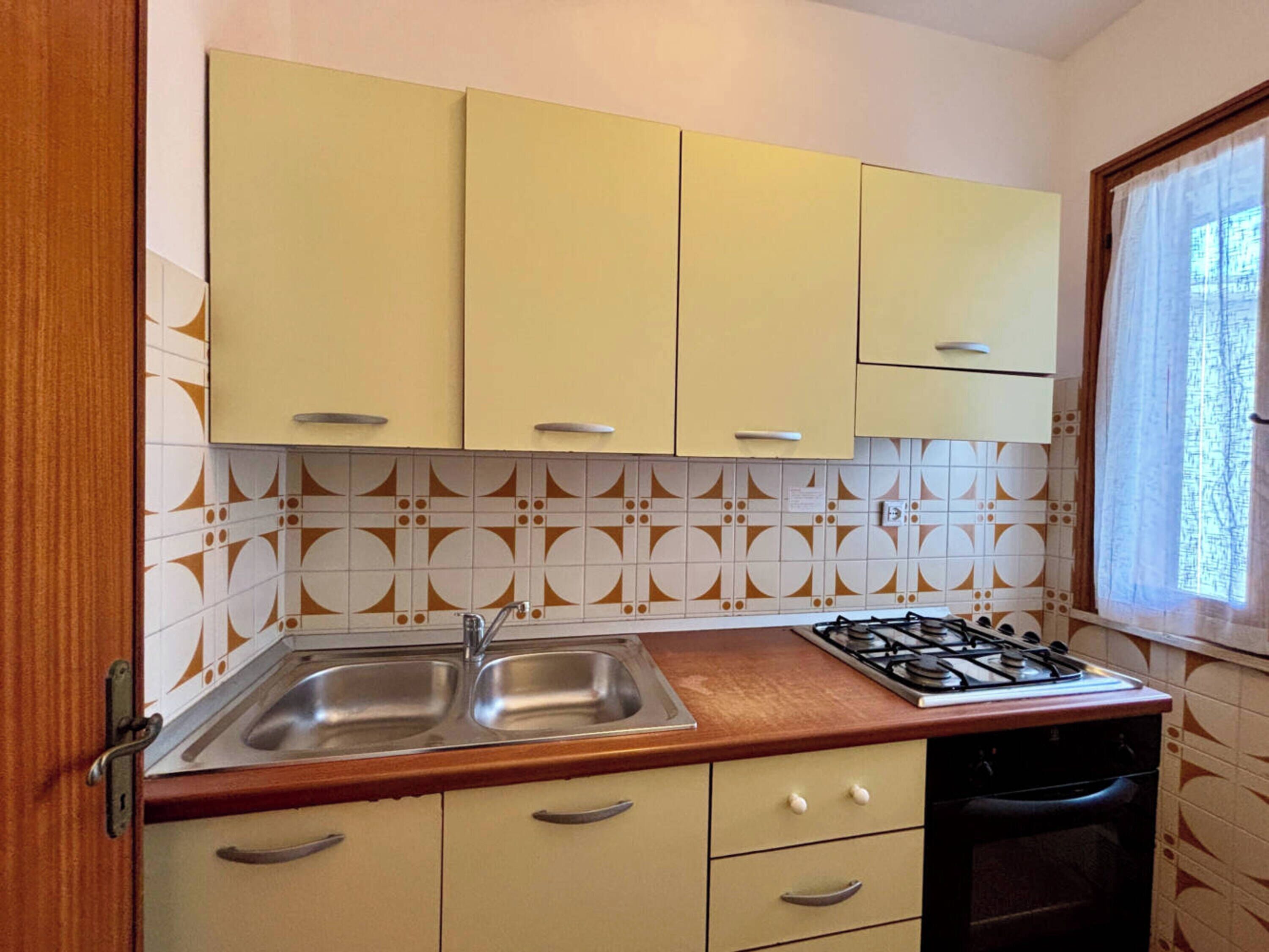 A kitchen with two sinks, a stove, and cabinets.