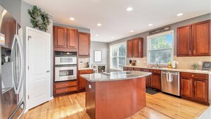 A modern kitchen with wooden cabinets, stainless steel appliances, and a large island. - Stay and Play Retreat - Family Home and Game Room (Bellevue)