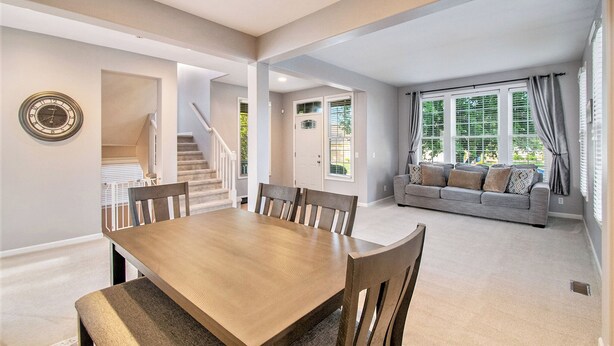 A spacious living area with a dining table and chairs, a sofa set, and a staircase leading to an upper floor. - Stay and Play Retreat - Family Home and Game Room (Bellevue)
