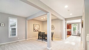 A spacious living area with a dining table and chairs, a kitchen in the background, and a large window with blinds. - Stay and Play Retreat - Family Home and Game Room (Bellevue)