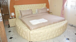 Quarto com uma cama grande, duas mesas de cabeceira, um guarda-roupa e porta de banheiro.