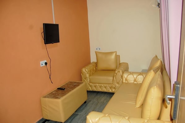 Una habitación con un sofá, una mesita y un televisor montado en la pared.