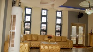 Sala de estar com sofá seccional bege, ventoinha branca e lustre.