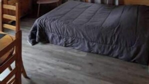 A room with a bed, a chair, a television, and a window with curtains. - Chalet en Bois à la Campagne (Cayres)