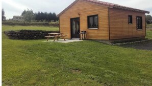 A small wooden cabin with a red roof, a door, and two windows. There is a picnic table outside. - Chalet en Bois à la Campagne (Cayres)