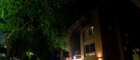 A building with a sign reading "treeboo" and "Living Room" at night.