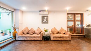 Un área de recepción con dos sofás, un jarrón con flores y un cuadro en la pared.