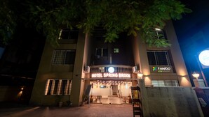 Entrada de un hotel con un letrero que dice "Hotel Spring Brook" y el logo de "Treebo".