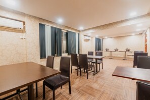 Un salón de conferencias con mesas y sillas, unidades de aire acondicionado y una pared con diseño.