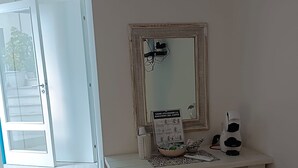 A room with a white desk, a mirror, a coffee machine, and a small refrigerator. There is a sign on the mirror and a door leading outside. - Double Room, air Conditioning, Bathroom, (Tropea)