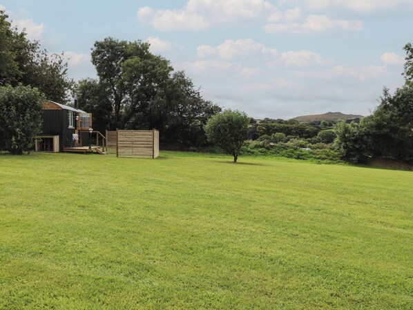 A grassy field with a small building and a wooden fence.