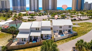 Una propiedad frente a la playa con varios edificios blancos, un área de piscina y vista al océano.