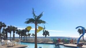 Zona junto a la piscina con sillas de descanso, una palmera y vista al océano.