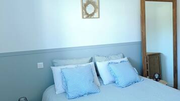 Quarto com cama, mesa de cabeceira, abajur e espelho.