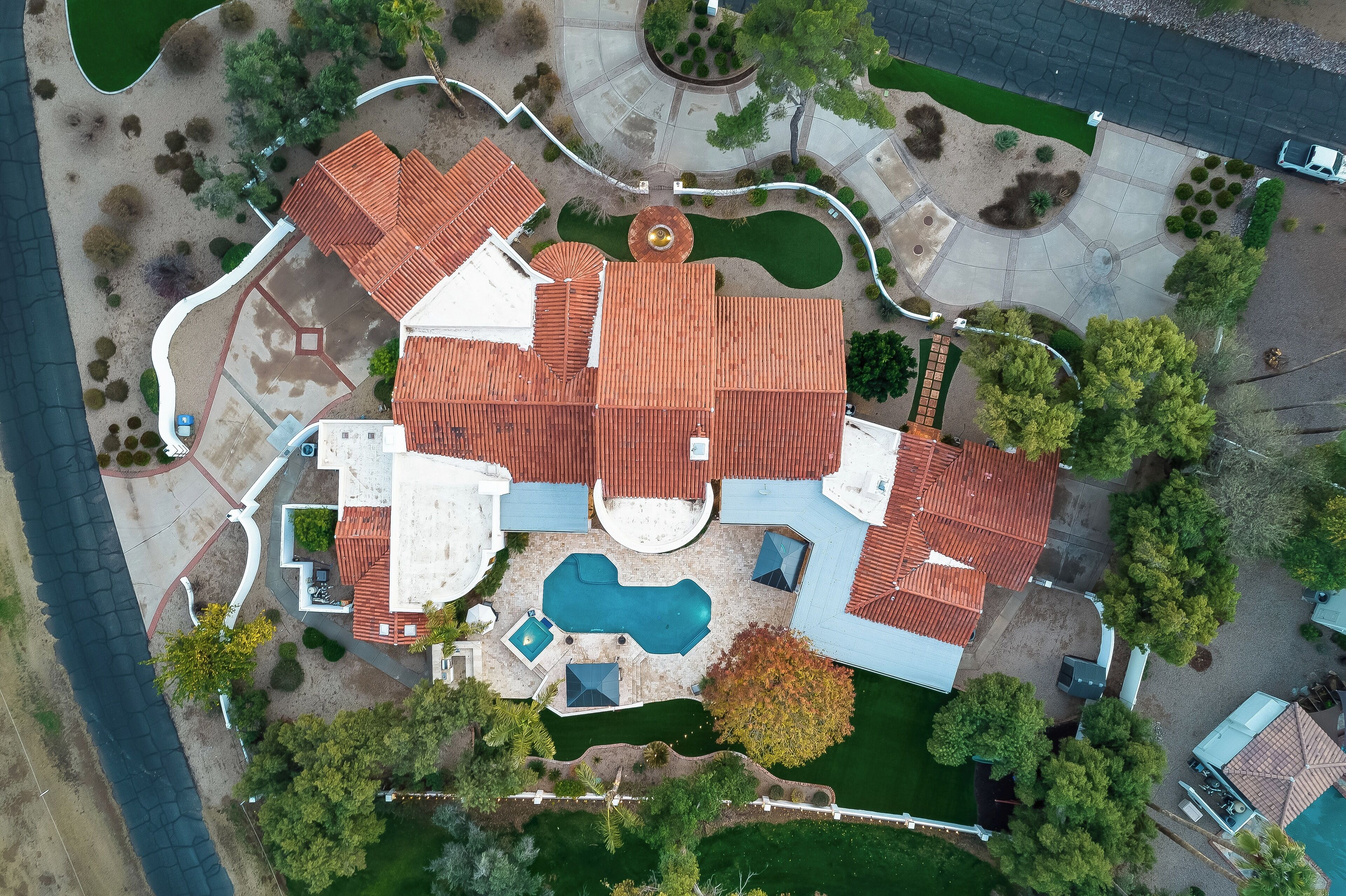 An aerial view of a residential property with multiple buildings, a swimming pool, and landscaped gardens.