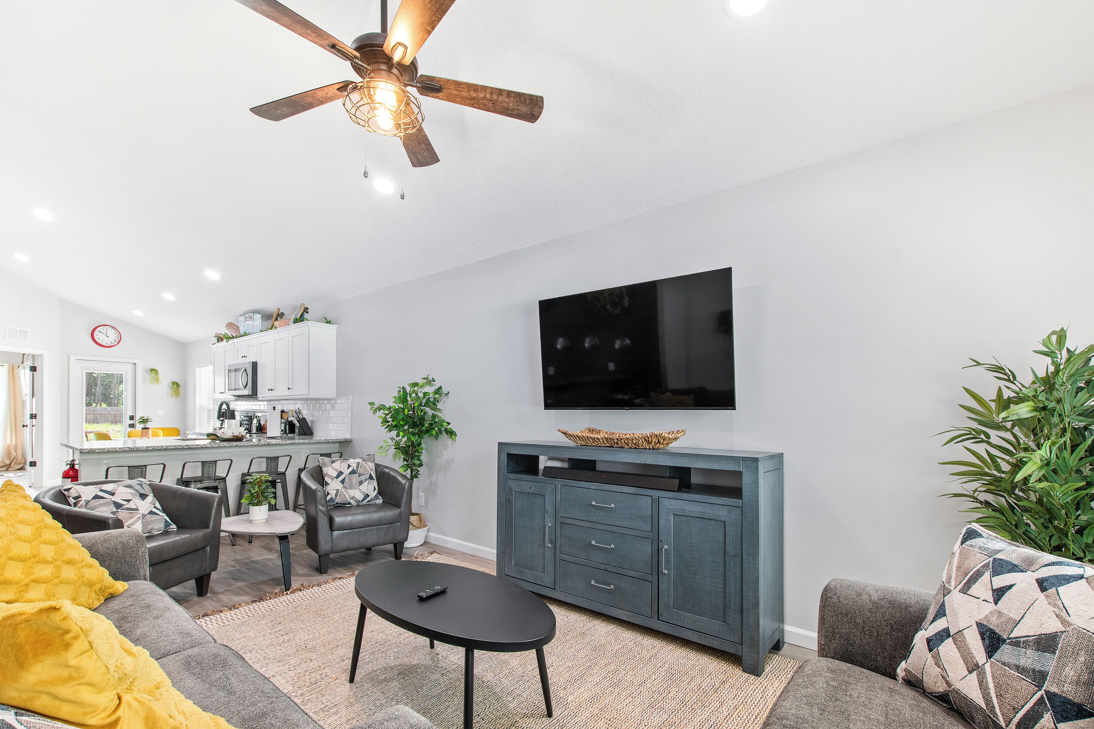 A modern living room with a grey sofa, a black coffee table, and a grey cabinet with a flat-screen TV.