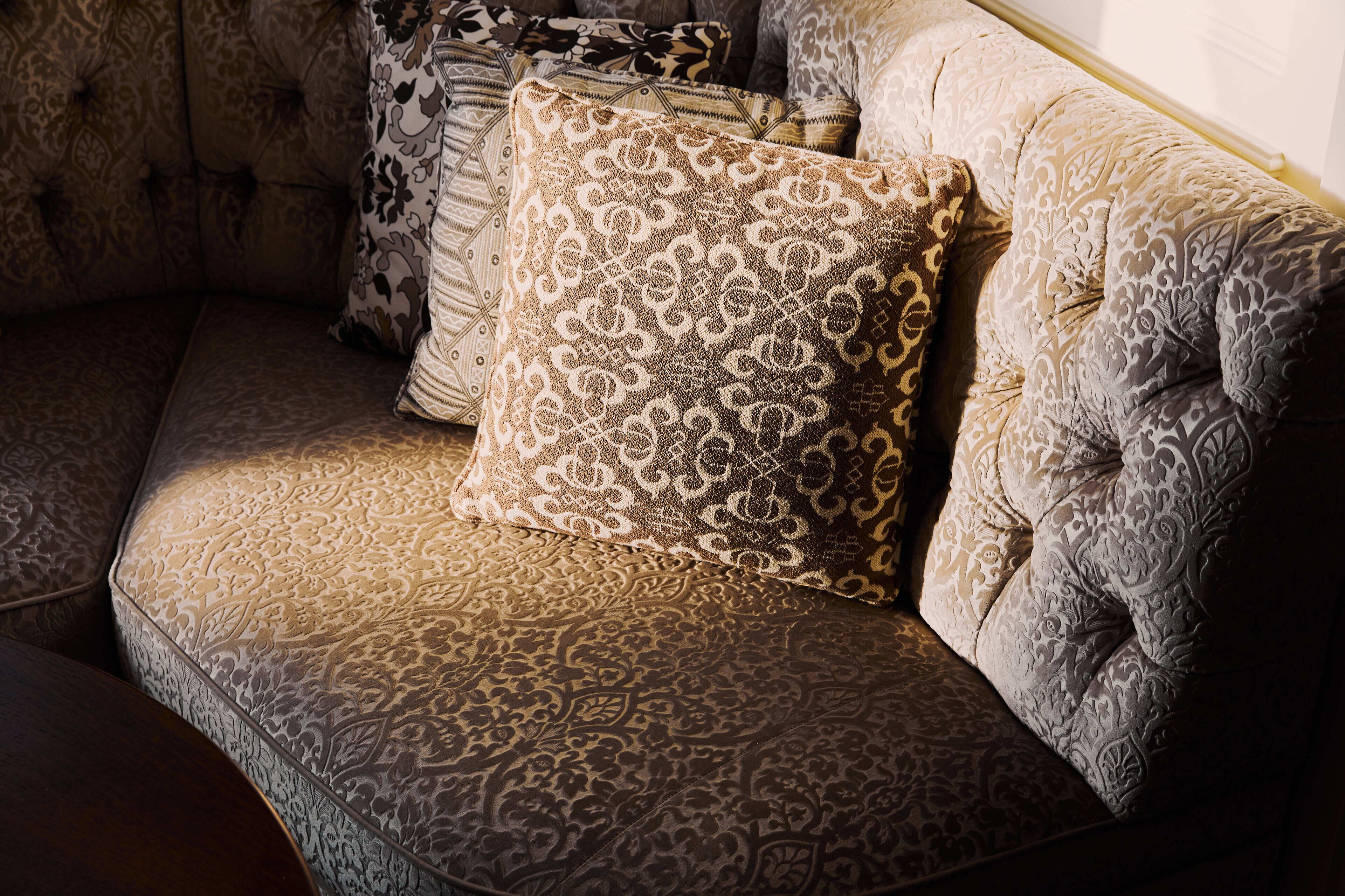 A corner of a room with a patterned sofa and multiple decorative pillows.