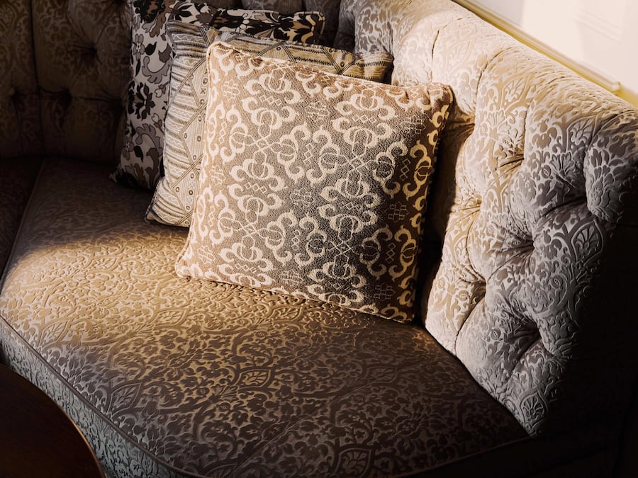 A corner of a room with a patterned sofa and multiple decorative pillows.