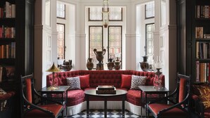 A room with a red sofa set, a chandelier, and a patterned floor. - At Sloane (London)