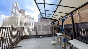 A rooftop terrace with a glass ceiling, a metal railing, and air conditioning units. - NAOMI (Osaka)