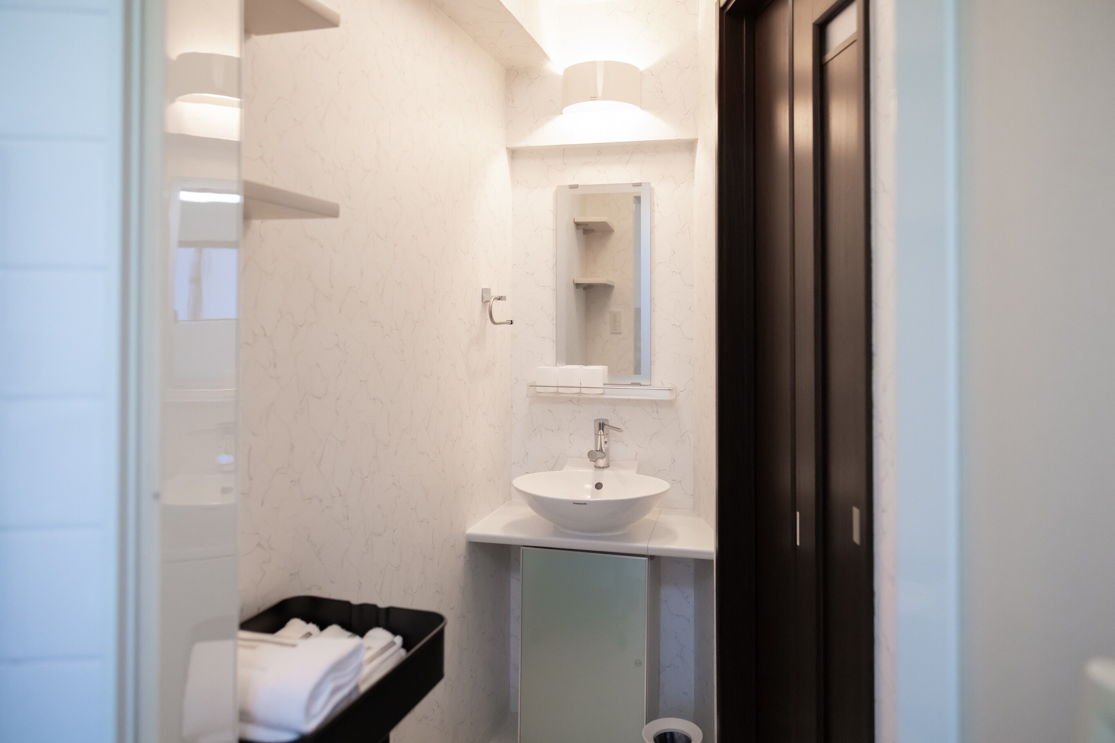 A modern bathroom with a white sink, mirror, and towel rack.