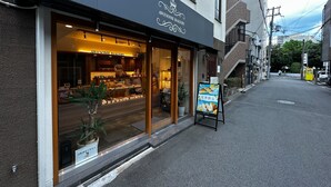 A bakery with a dark facade and large display windows. - NAOMI (Osaka)