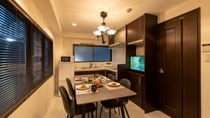 A modern kitchen with a dining table, chairs, and a television. - NAOMI (Osaka)