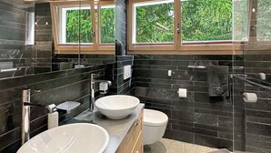 Un baño moderno con dos lavamanos, un inodoro y una zona de ducha.