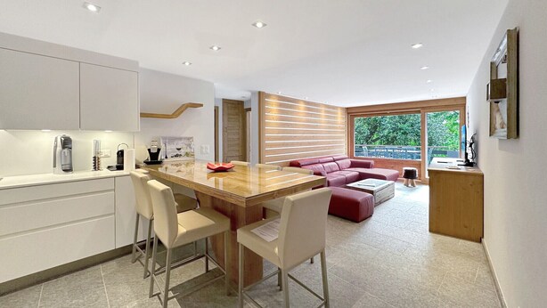 Una cocina moderna con comedor, un sofá rojo y un amplio ventanal.