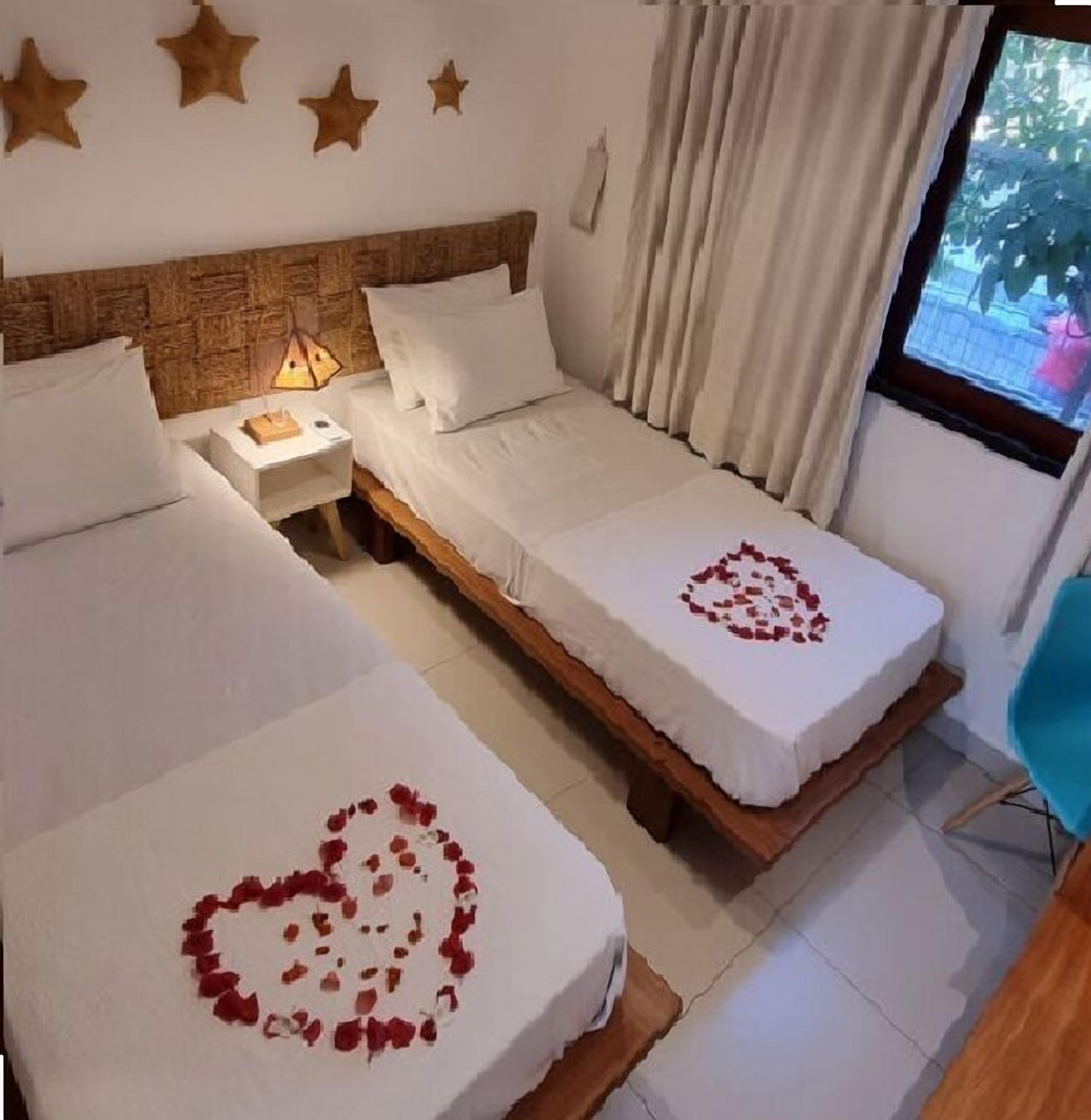 Ein Schlafzimmer mit zwei Betten, einem Holzkopfstück, einem Nachttisch, einer Lampe und einem Fenster mit Vorhängen.