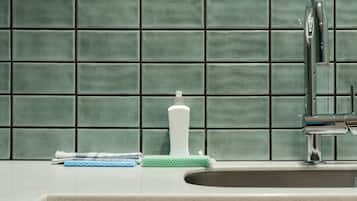 A kitchen with a tiled backsplash, a sink, a faucet, a bottle, and a cloth.