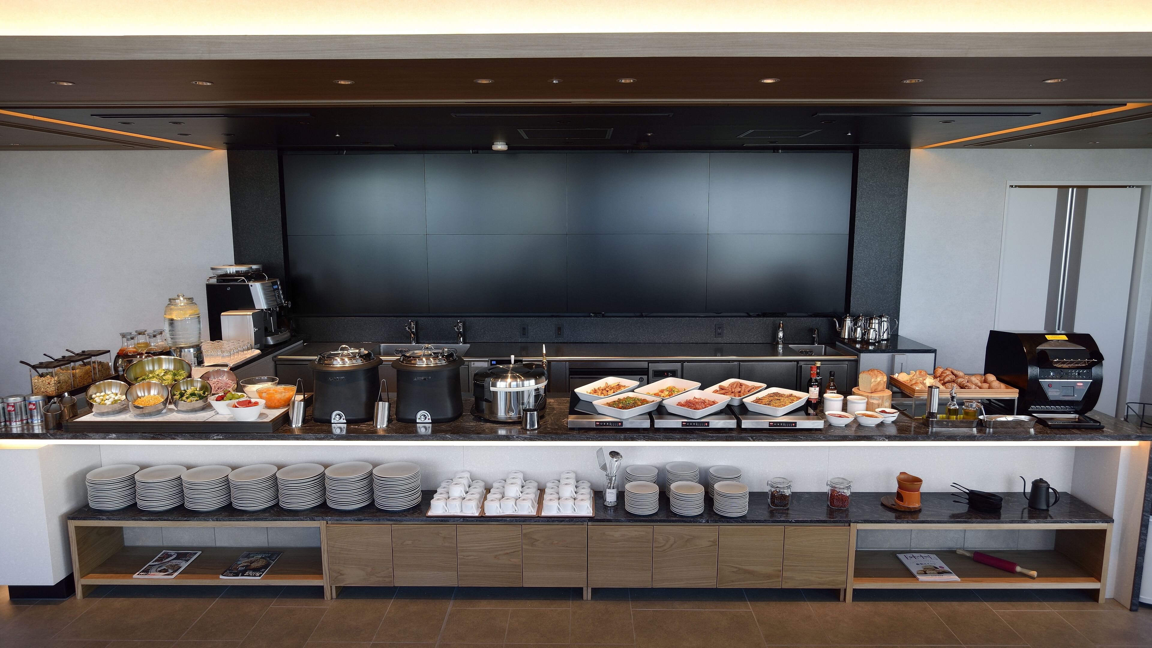 A buffet setup with various food items, coffee machines, and a coffee press.