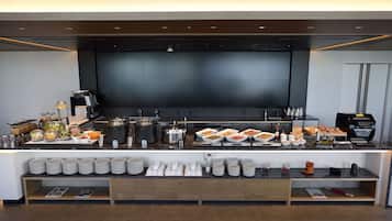 A buffet setup with various food items, coffee machines, and a coffee press.