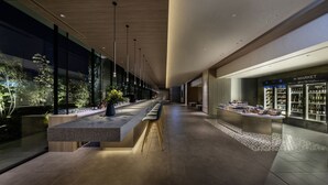 Un couloir moderne avec un long bar, un magasin H MARKET et une vue sur la verdure à l’extérieur.