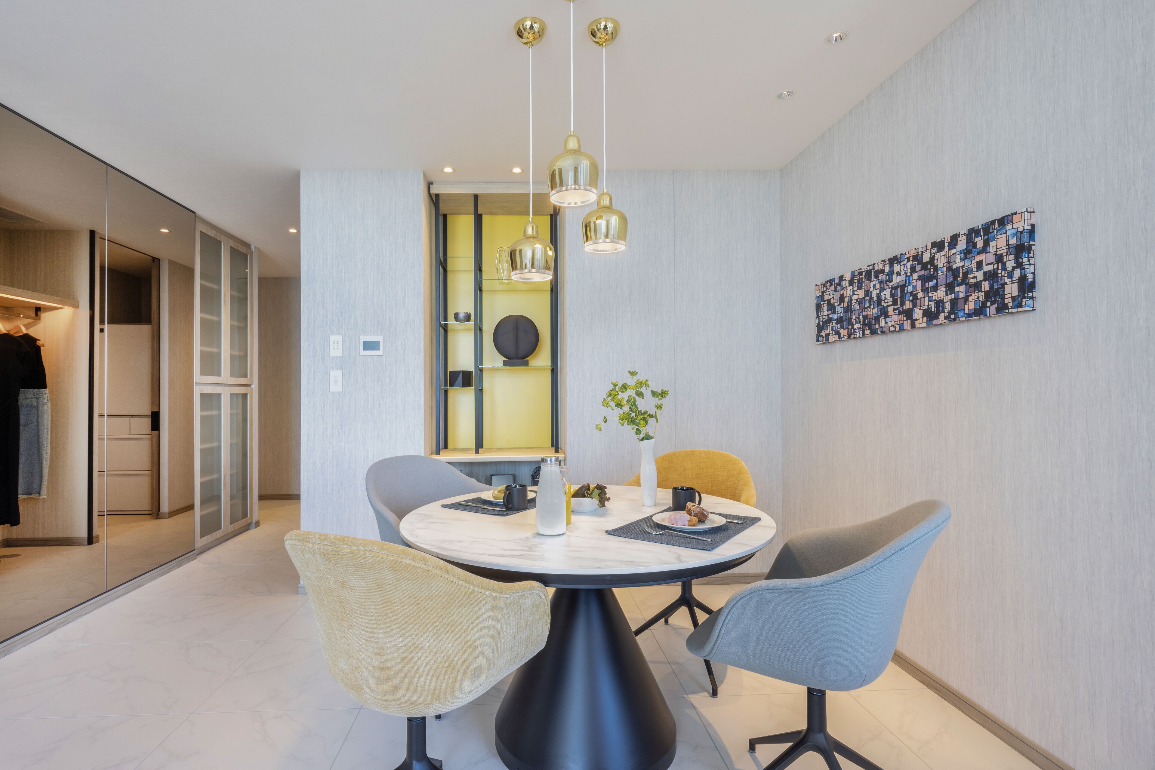 A modern dining area with a round table, four chairs, and pendant lighting.