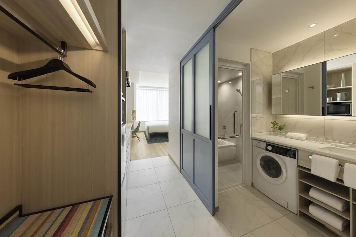 A modern bathroom with a washing machine, a large mirror, and a shower.