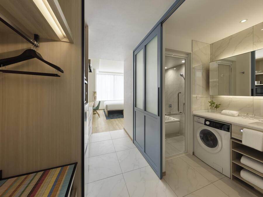 Un baño moderno con lavadora, un espejo grande y ducha.